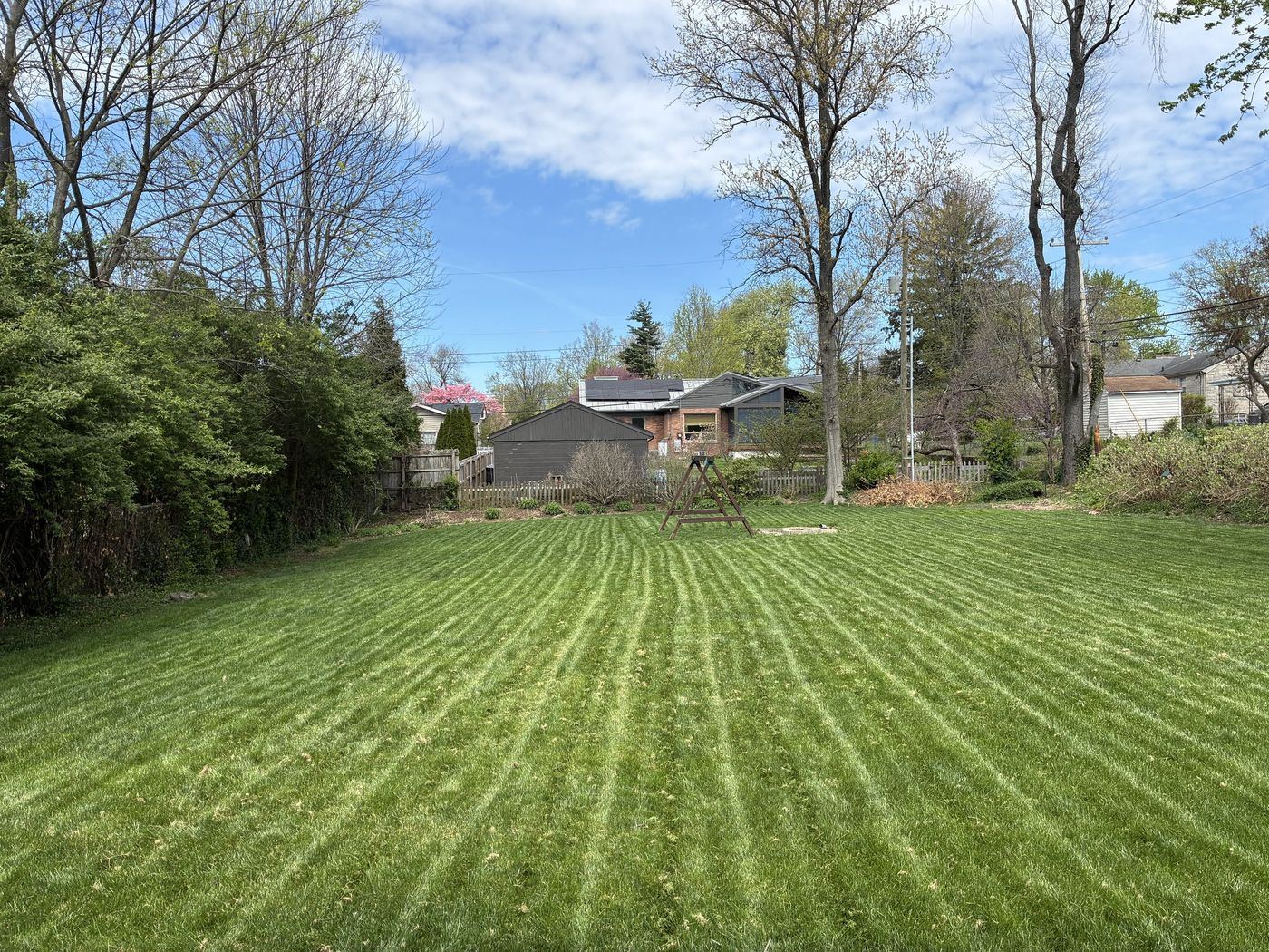 Backyard with crisp mowing stripes under blue sky — a Mowing and Moore job in Lexington, KY